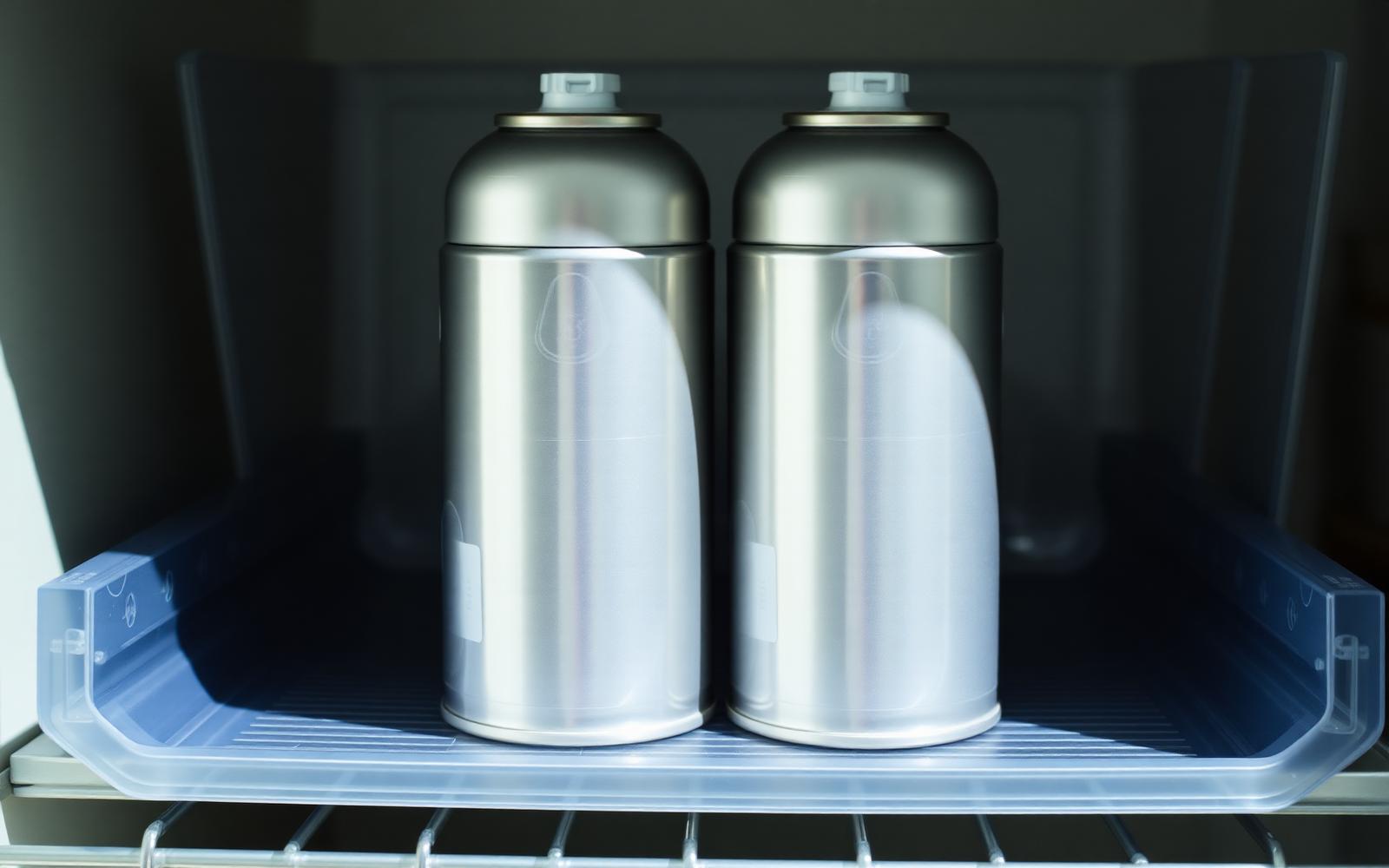 Aerosol styling cans stored upright in a rigid plastic bin on a cool shaded shelf away from heat
