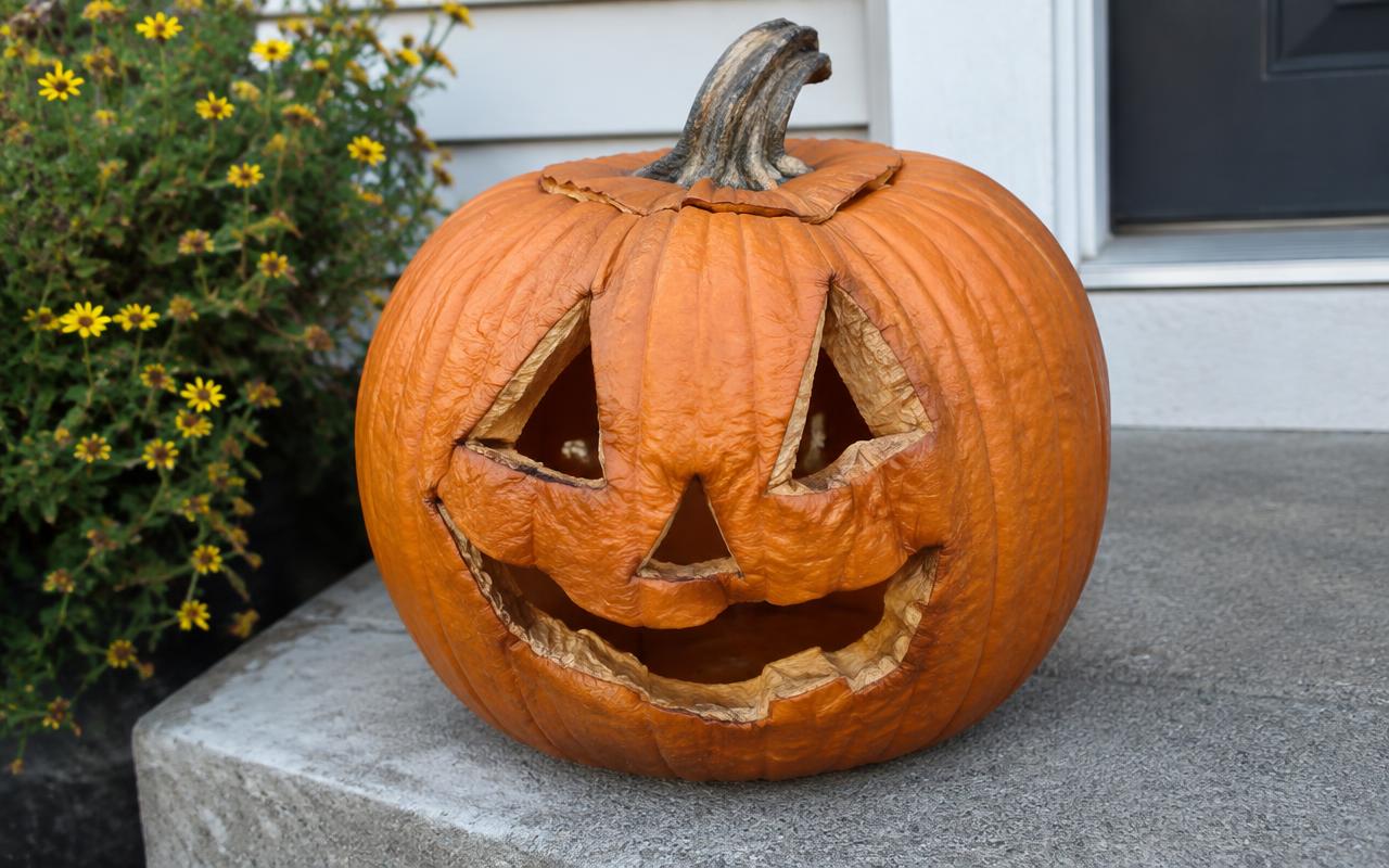 Carved pumpkin jack o lantern softening and wrinkling at the cut edges on porch steps