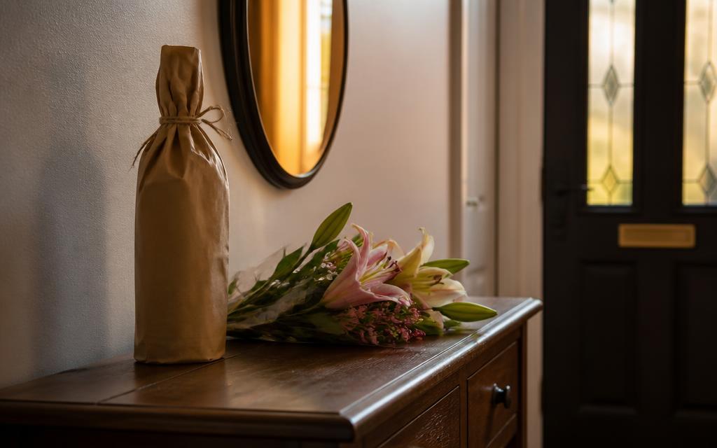 Dinner party host gift of a wrapped bottle and flowers waiting by the front door