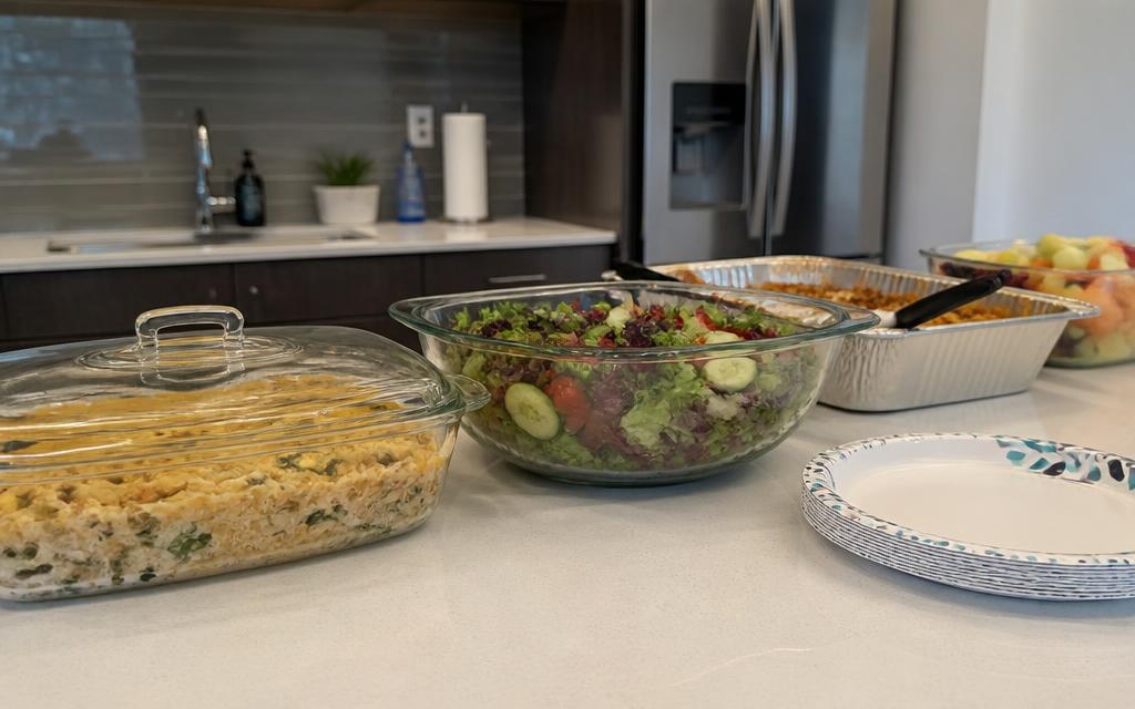 Covered glass casserole dish on an office kitchen counter with other potluck dishes