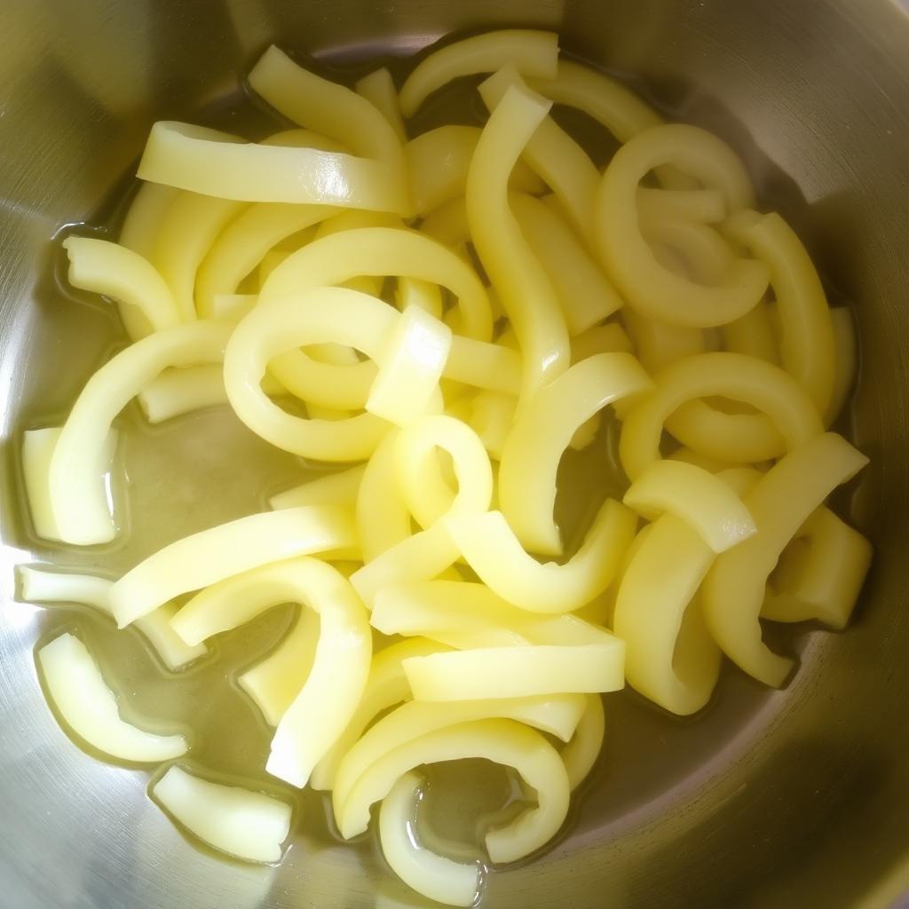 Pale sliced yellow onions starting to soften in melted butter in a stainless steel skillet